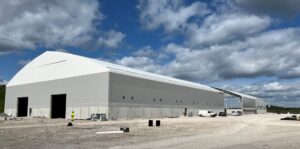 Rakennusvaiheessa oleva pitkä harmaavalkoinen halli.